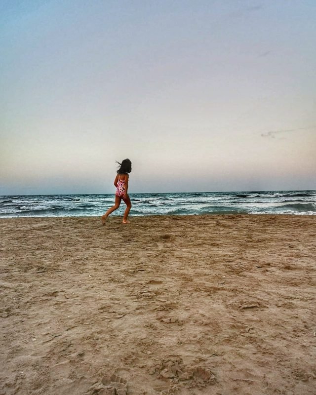 criança correndo na areia da praia